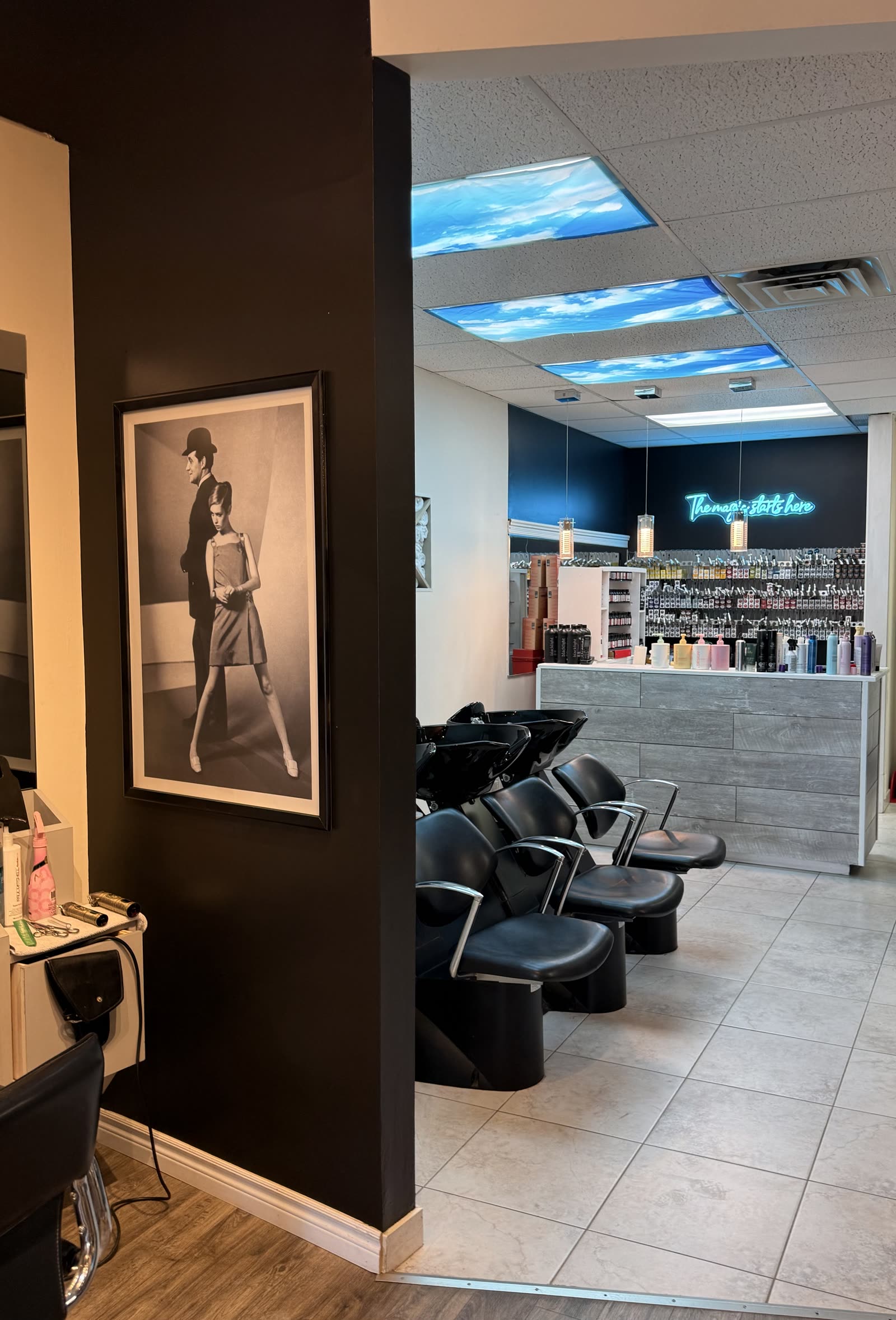 Wash stations and retail wall at Michael of London Salon, featuring a Twiggy portrait and sky-panel ceiling